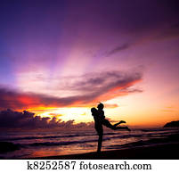 Silhouette of happy couple embracing on the beach