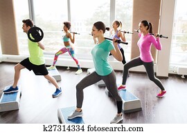 group of people exercising with barbell in gym