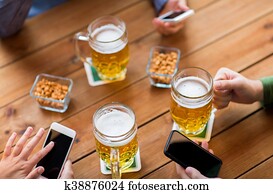 close up of hands with smartphones and beer at bar close up of hands with smartphones and beer at bar