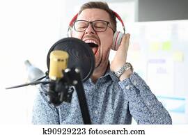 Young man in headphones singing into microphone