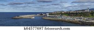 Panoramic View of colorful quay and port of village Rabo de Peixe with boats, church and lighthouse in Sao Miguel, the largest of the Azores Islands, Portugal. Sunny cloudy day