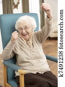 Senior Woman Celebrating In Chair At Home Senior Woman Celebrating In Chair At Home