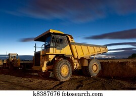 Huge auto-dump yellow mining truck night shot and excavator