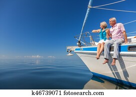 Happy Senior Couple Sitting on the Side of a Sail Boat Happy Senior Couple Sitting on the Side of a Sail Boat