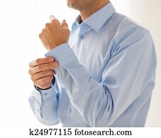 close up of man fastening buttons on shirt sleeve