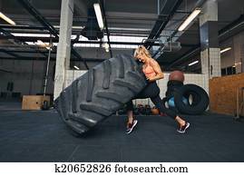 Crossfit woman flipping a huge tire at gym Crossfit woman flipping a huge tire at gym