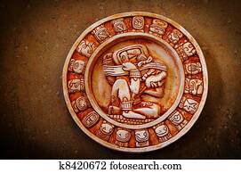 A carved Mayan calendar on textured background