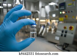 Hand in rubber glove holding a bottle of medicine Hand in rubber glove holding a bottle of medicine