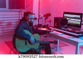 Professional musician recording guitar in digital studio at home, Music production technology concept.
