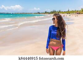Puerto Rico beach vacation woman relaxing in San Juan wearing rash guard solar protection surf clothing and bikini happy on summer holidays travel destination. Puerto Rico beach vacation woman relaxing in San Juan wearing rash guard solar protection surf clothing and bikini happy on summer holidays travel destination.
