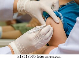 Doctor give injection of vaccine to boy's arm Doctor give injection of vaccine to boy's arm