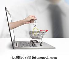 Hand from laptop screen taking house key in shopping cart