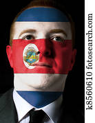 High key portrait of a serious businessman or politician whose face is painted in national colors of costa rica flag