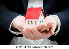 A real estate agent holding a small new house in her hands