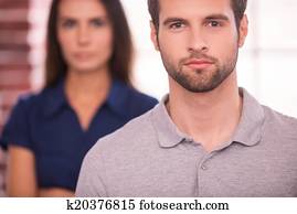 jung, und, successful., sicher, junger mann, anschauen kamera, während, frauenansehen, hinter, ihm, und, beibehaltung, verschränkte arme