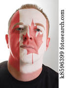 Face of serious patriot man painted in colors of canada flag