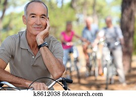 Senior on a bike with friends in the background
