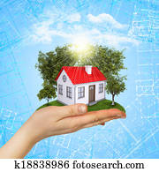 Hands holding a small house with land