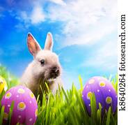 Little Easter bunny and Easter eggs on green grass Little Easter bunny and Easter eggs on green grass