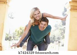 Young Man Giving Woman Piggyback Outdoors Young Man Giving Woman Piggyback Outdoors