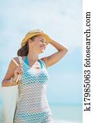 Portrait of happy young woman with hat and bag on sea shore