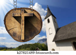 Wooden Cross on Tree Trunk with Small Church