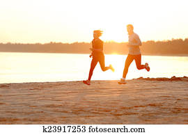 Young man and woman running along the waterfront