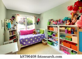 Girls bedroom with many toys and purple bed. Girls bedroom with many toys and purple bed.