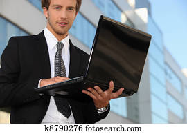 Young business outside office with laptop computer
