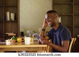 African man sitting at home using digital tablet