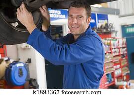Mechanic working under car smiling Mechanic working under car smiling