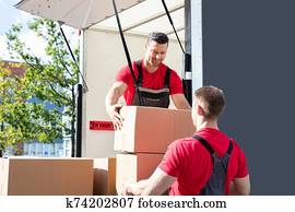 Two Male Worker Loading The Cardboard Boxes In Moving Truck Two Male Worker Loading The Cardboard Boxes In Moving Truck