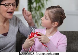 grandmother singing while her granddaughter is knitting