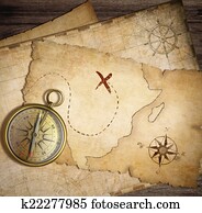 aged brass nautical compass on table with old treasure maps