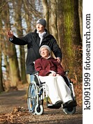 elderly woman in wheelchair walking with son