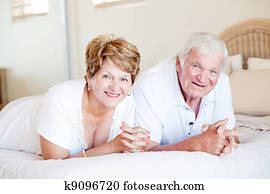 happy senior couple lying on bed