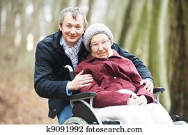 old senior woman in wheelchair with careful son old senior woman in wheelchair with careful son
