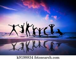 People and dog jumping on the beach. Happiness