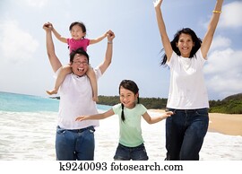 happy asian family jumping on the beach