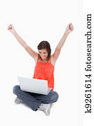 Teenager showing her satisfaction behind her laptop while raisin