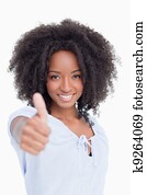 Woman smiling and standing upright while placing her thumbs up in satisfaction