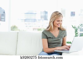 Woman using her laptop on the couch and smiling