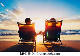 senior couple of old man and woman sitting on the beach watching sunset senior couple of old man and woman sitting on the beach watching sunset