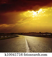 asphalt road to dramatic sunset