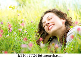 Beautiful Young Woman lying in Meadow of Flowers. Enjoy Nature 