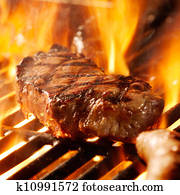 beef steak on the grill with flames.