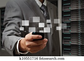 business man holds touch screen mobile phone in server room