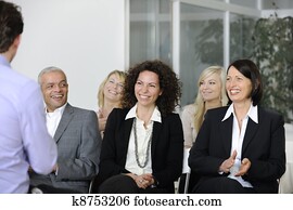 Business team listening smiling to speaker Business team listening smiling to speaker