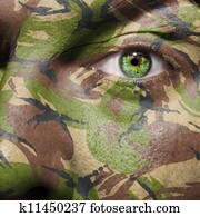 Camouflage painted on a face with green eye Camouflage painted on a face with green eye