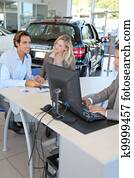 Car seller and couple of buyers signing contract